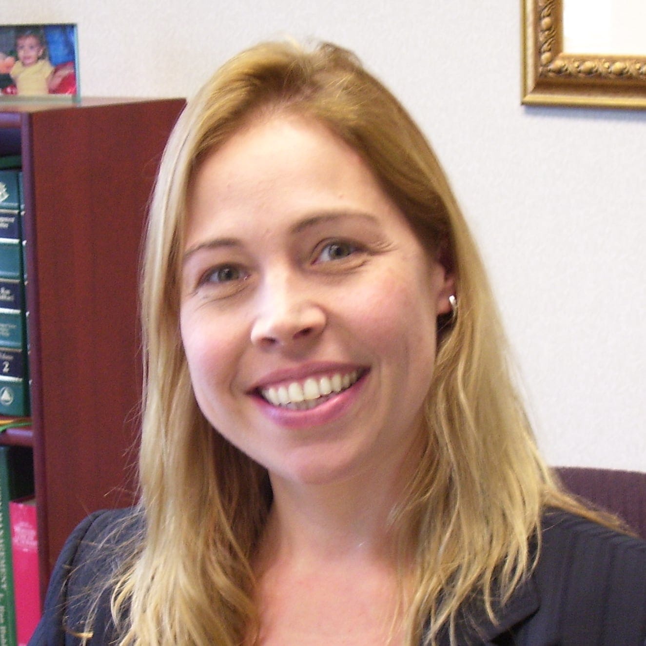 A smiling Carla Dezelic sitting at a desk.