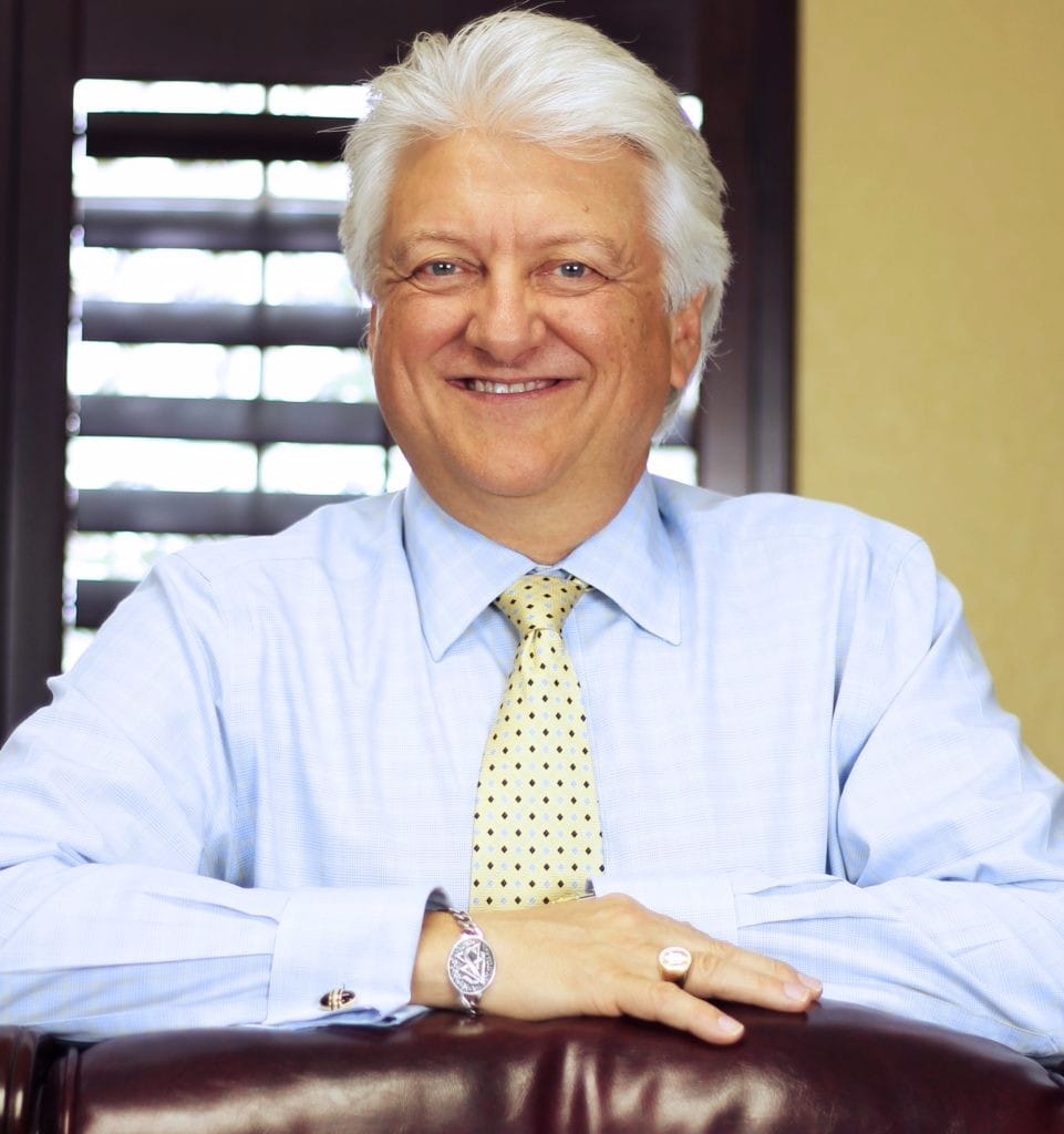 Dr. Greg Winteregg smiling at the camera with arms folded resting on a countertop facing the camera